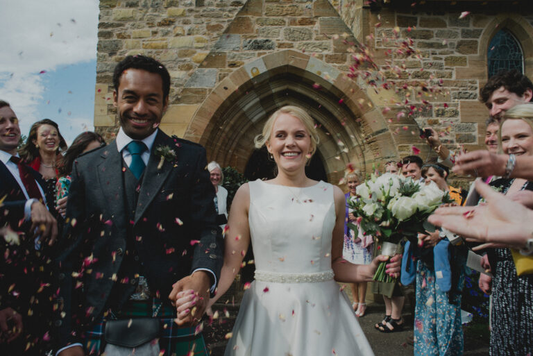 Bride and groom getting confetti thrown at them whilst exit the church in Aberlady